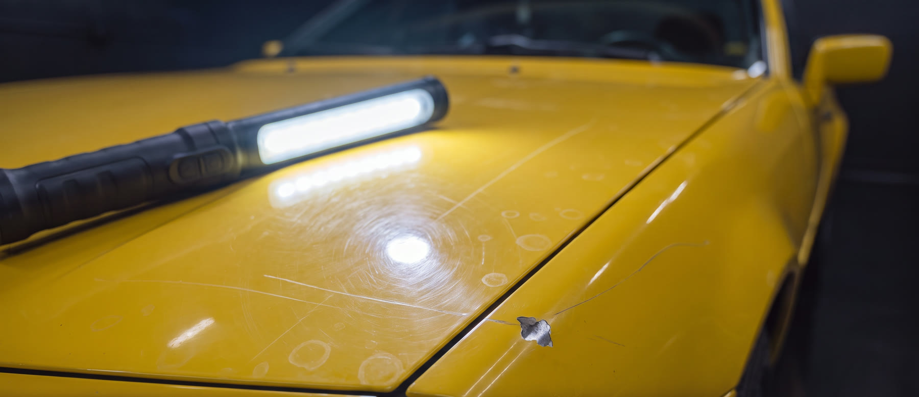 Close-up of paint under an inspection light showing swirl marks and scratches